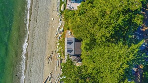 Luftaufnahme eines Strandes mit einem Haus und Booten.