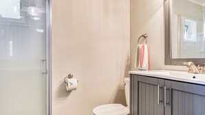 Ein modernes Badezimmer mit Duschkabine aus Glas, einer weißen Toilette und einem Waschtisch mit Spiegel.