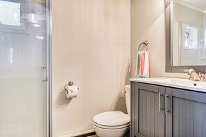 A modern bathroom with a glass shower enclosure, a white toilet, and a vanity with a mirror. - Oceanfront Studio w/ World Class Views & Patio (Point Roberts)