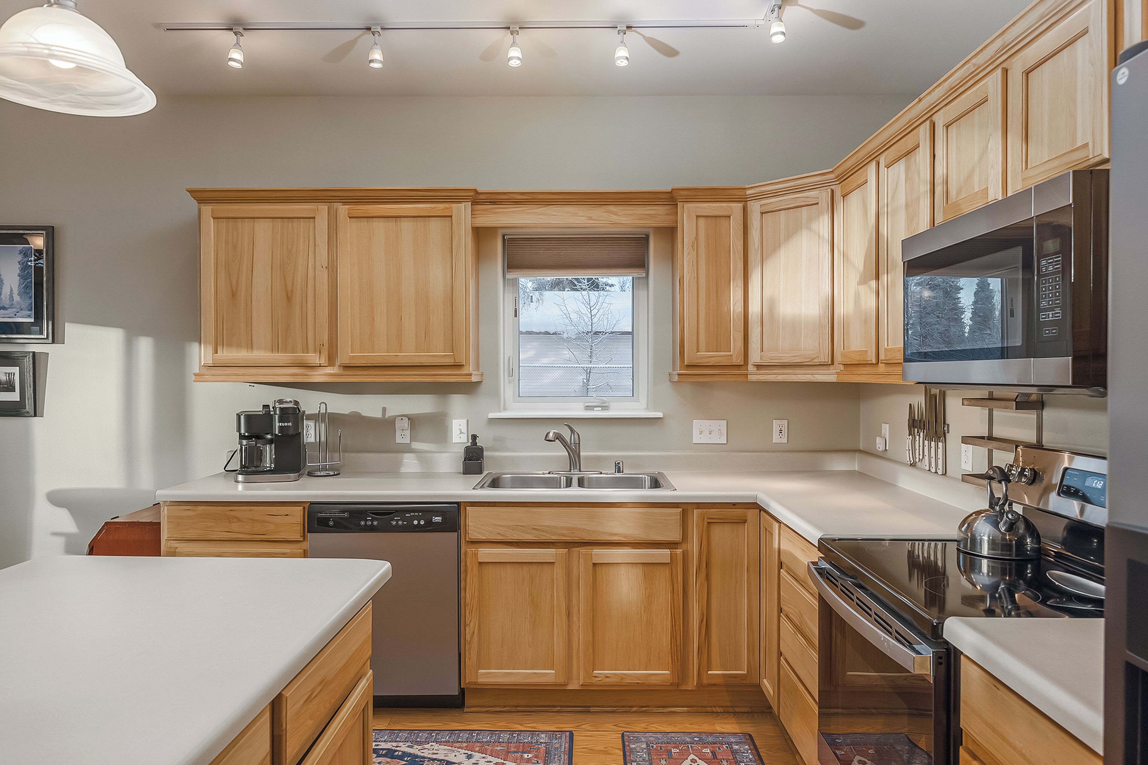 Una cocina moderna con armarios de madera, electrodomésticos de acero inoxidable y un ventanal que proporciona luz natural.