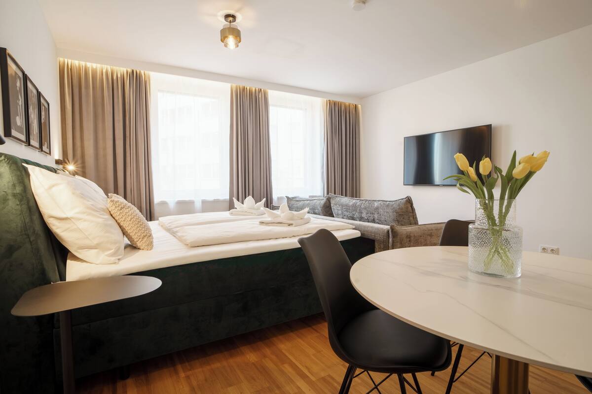 Una habitación de hotel moderna con cama, una mesa de comedor y televisor.