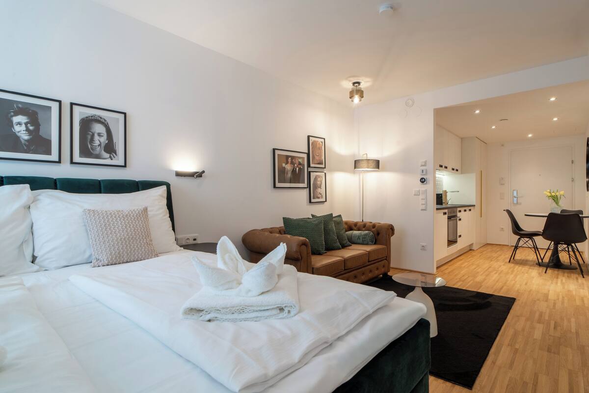 Una habitación de hotel con cama, sofá, zona de comedor y cocina.