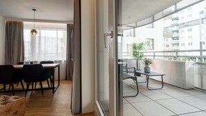 A modern apartment with a dining area, a balcony with a potted plant, and a view of a building.