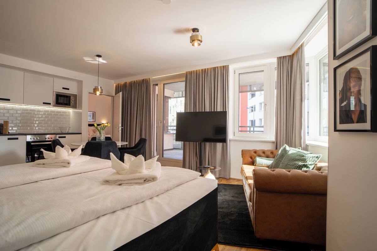 Una habitación de hotel con cama, televisor, sofá y zona de comedor.