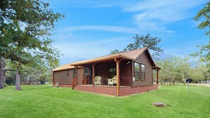 A log cabin with a porch, a small deck, and a single window. - Water-view Cabin w/ Front Porch, W & D, Streaming (Carmine)