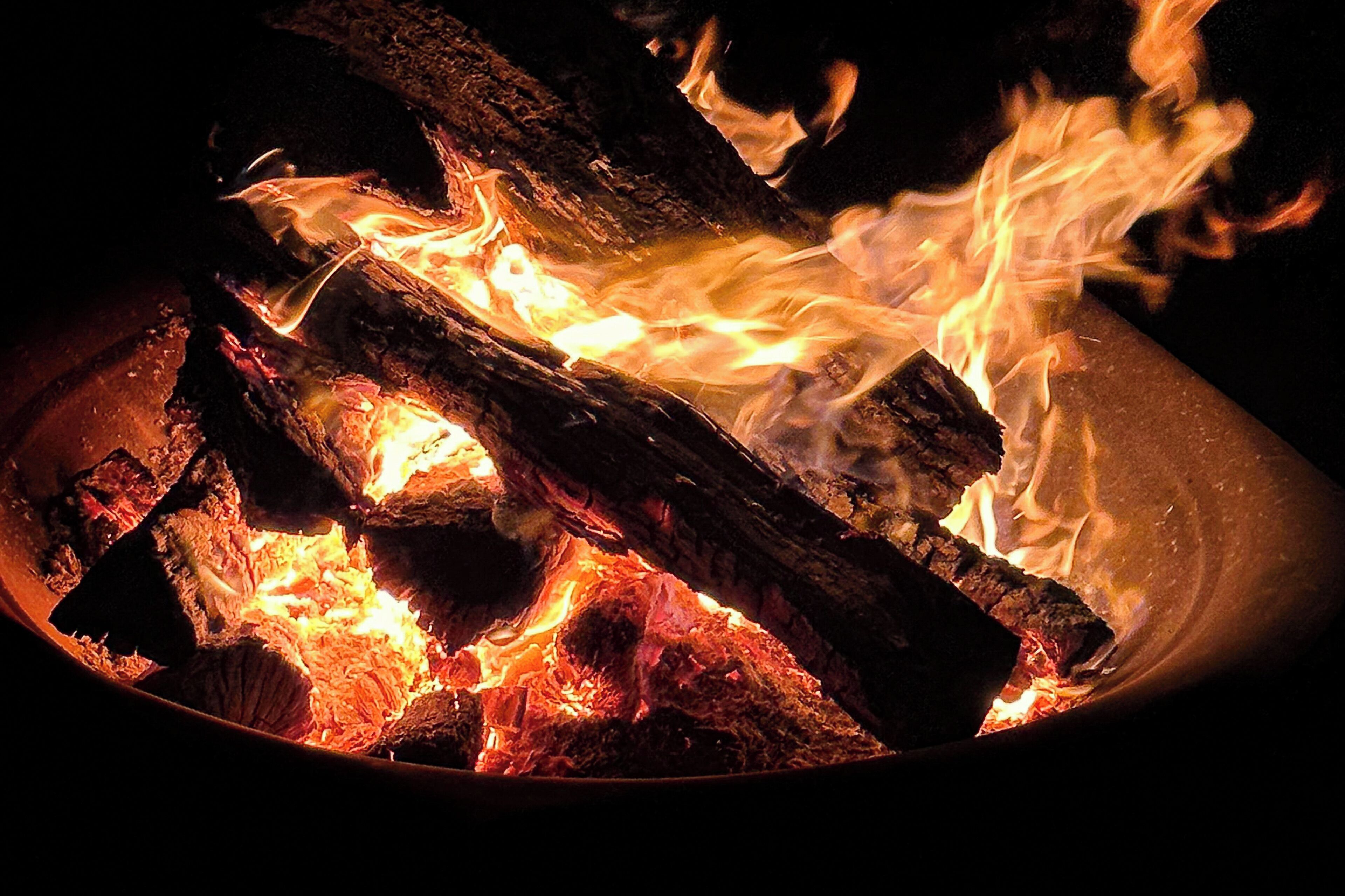 Un primo piano di un fuoco che arde in un contenitore metallico.
