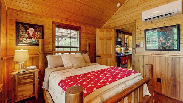 Camera da letto in una baita di legno, con un letto, un comodino e una finestra.
