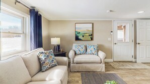 A living room with a beige sofa, a matching armchair, a wooden coffee table, and a painting on the wall. - 12 Mi to Lake George! Quiet Adirondack Escape (Fort Ann)
