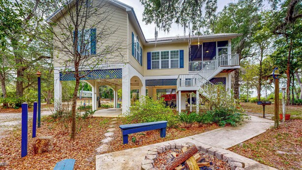 A two-story house with a porch, a fire pit, and a bench. - Dog-friendly Riverfront 3BR w/ Fire Pit & Dock (Bell)