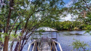 A wooden dock leading to a covered pavilion by a calm river, surrounded by trees. - Dog-friendly Riverfront 3BR w/ Fire Pit & Dock (Bell)