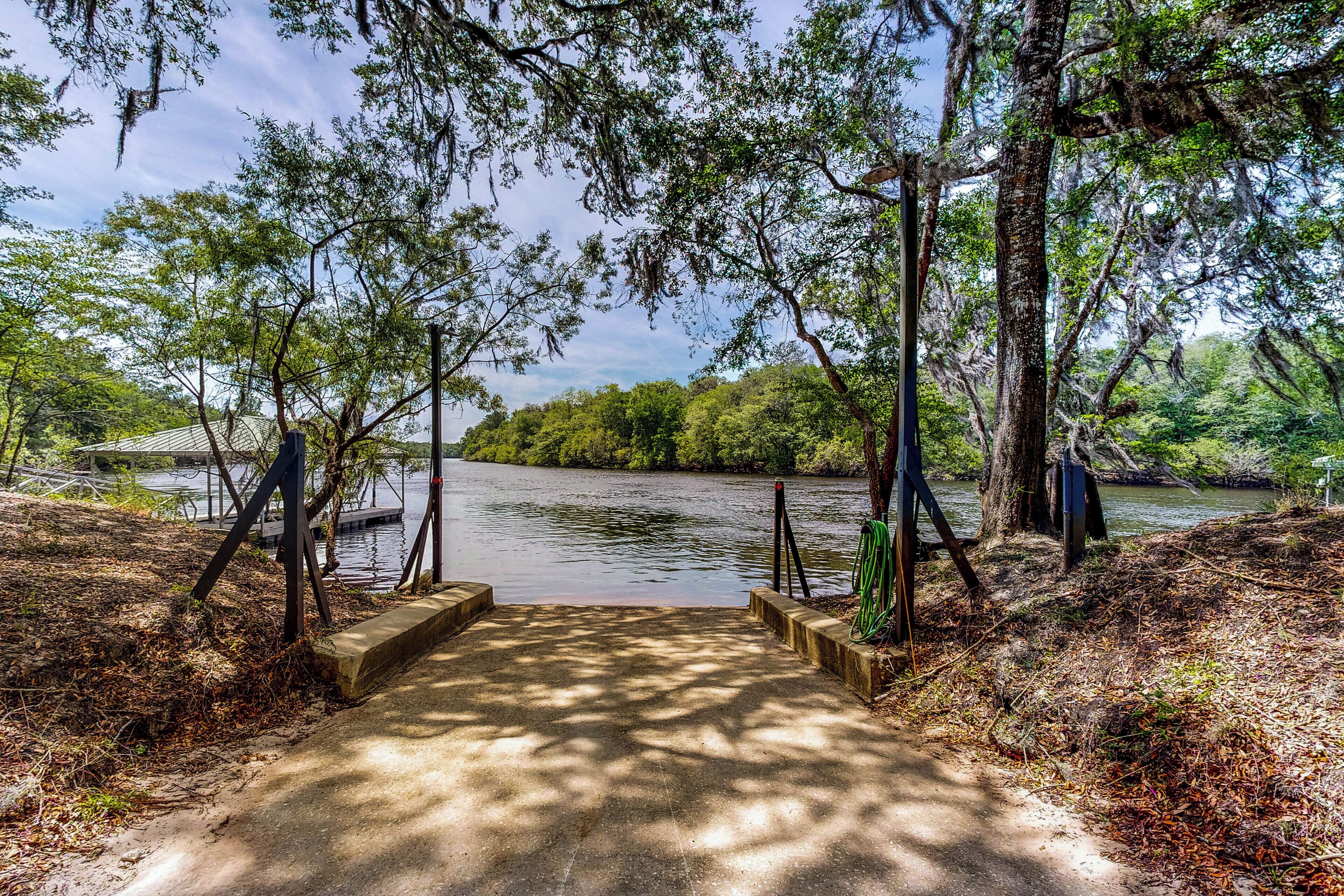 A concrete pathway leading to a body of water surrounded by trees.