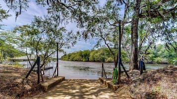 A concrete pathway leading to a body of water surrounded by trees.