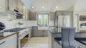 A modern kitchen with grey cabinets, stainless steel appliances, and a window providing natural light. - Outdoor Wonderland! Home 12 Mi to Lake George (Fort Ann)