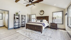 A bedroom with a large bed, a ceiling fan, a round mirror, and a window. - Outdoor Wonderland! Home 12 Mi to Lake George (Fort Ann)