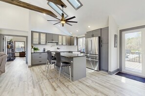 Una cocina moderna con una isla central, gabinetes grises, electrodomésticos de acero inoxidable y un ventilador de techo.