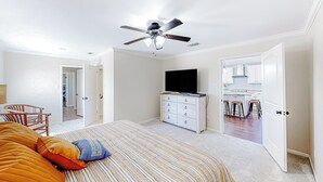 Une chambre à coucher avec un lit, un ventilateur de plafond, une commode et un téléviseur.