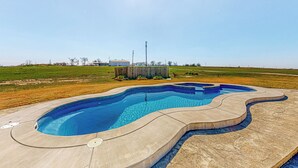 Une piscine dont le bord présente un motif ondulé, entourée d’une terrasse en béton.