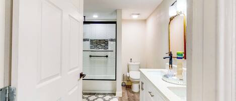 A bathroom with a shower, toilet, and vanity.
