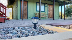 A green wooden building with a porch, a wooden bench, and a stone pathway leading to the entrance. - 1BR Casita w/ Mountain Views, Kitchenette, Wifi (Rimrock)