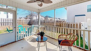 A covered patio with a ceiling fan, two wicker chairs, a small table, and a view of a fenced backyard. - Family-friendly Cameron Escape w/ Community Perks (Cameron)