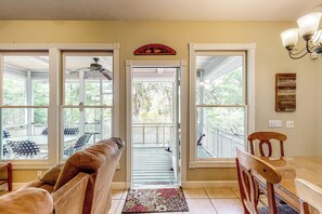 Una habitación amplia con un ventanal grande, un ventilador de techo y una mesa de comedor de madera con sillas.