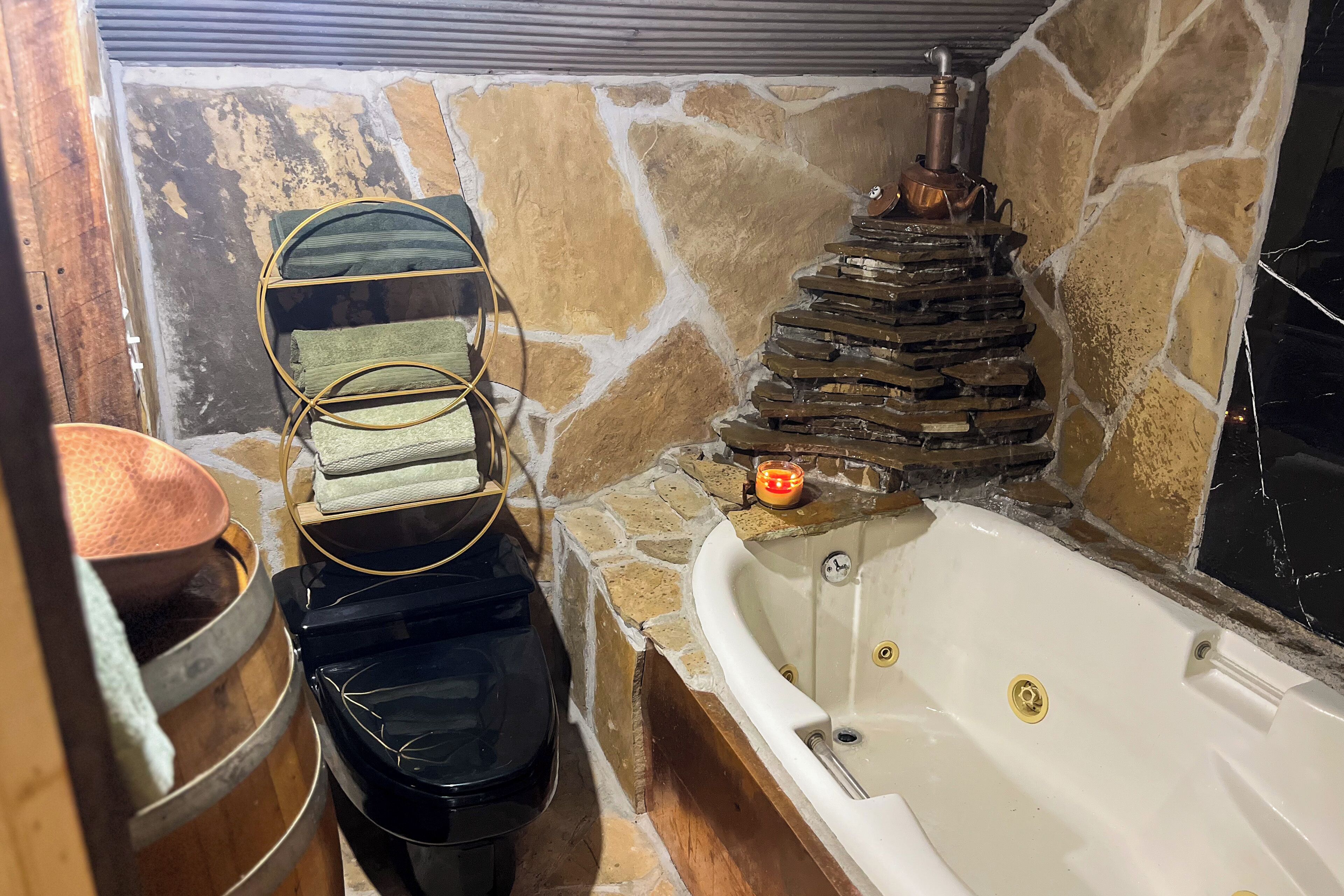 Une salle de bain avec un mur en pierre, une baignoire, une cheminée en pierre et un porte-serviettes.