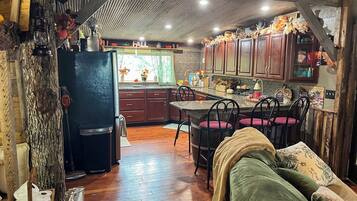 Une cuisine rustique avec des meubles en bois, un coin repas avec une table et des chaises, et un espace de vie chaleureux avec un canapé.