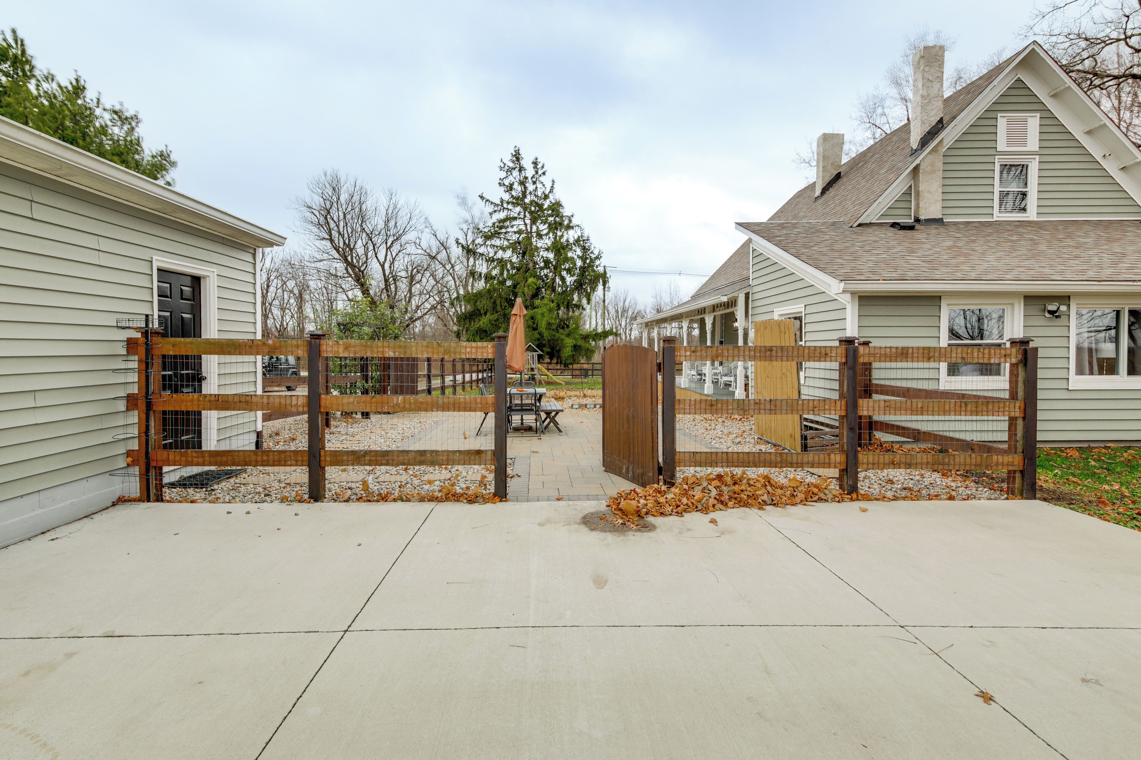 A gated driveway leading to a residential property with a covered patio area and a visible chimney.