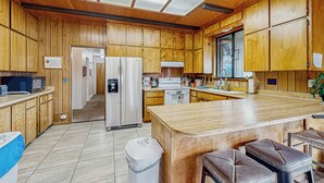 A kitchen with wooden cabinets, a central island, and a trash can. - 3BR Rustic Riverfront Home w/ Wood Stove (Blairsden-Graeagle)