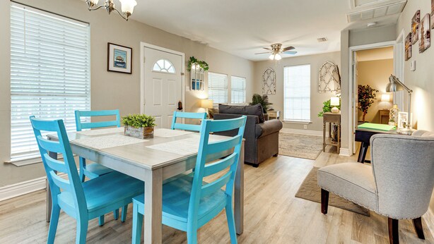 A dining area with a table and chairs, a ceiling fan, and a view of the living room. - Endless Entertainment! Unique & Cozy Theodore Home (Theodore)