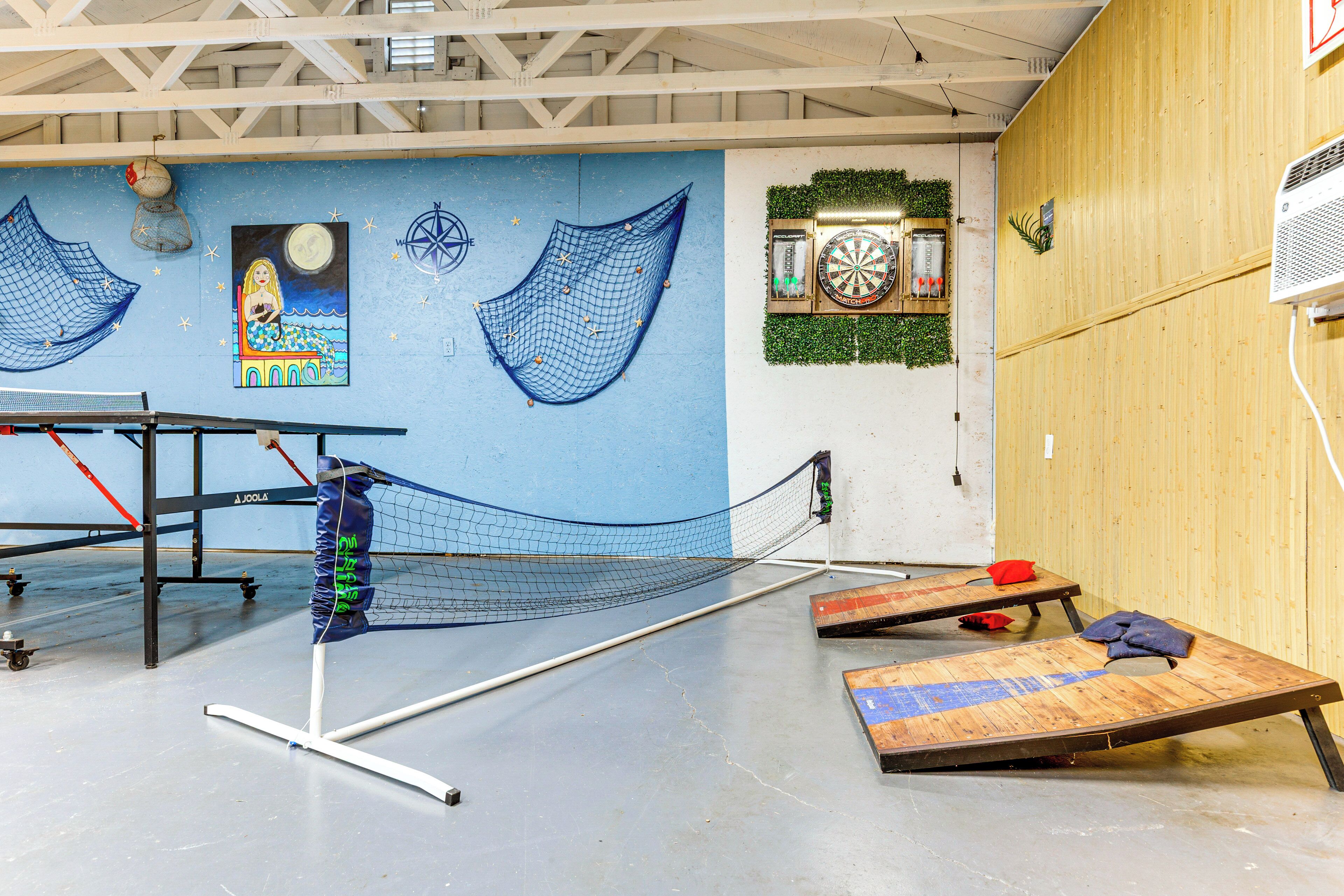 A ping pong table with a net, a dartboard, and a dartboard with a clock.