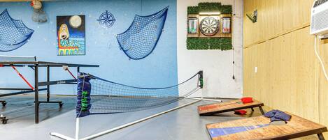 A ping pong table with a net, a dartboard, and a dartboard with a clock.