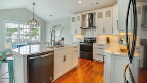 Una cocina moderna con armarios blancos, electrodomésticos de acero inoxidable y piso de madera.