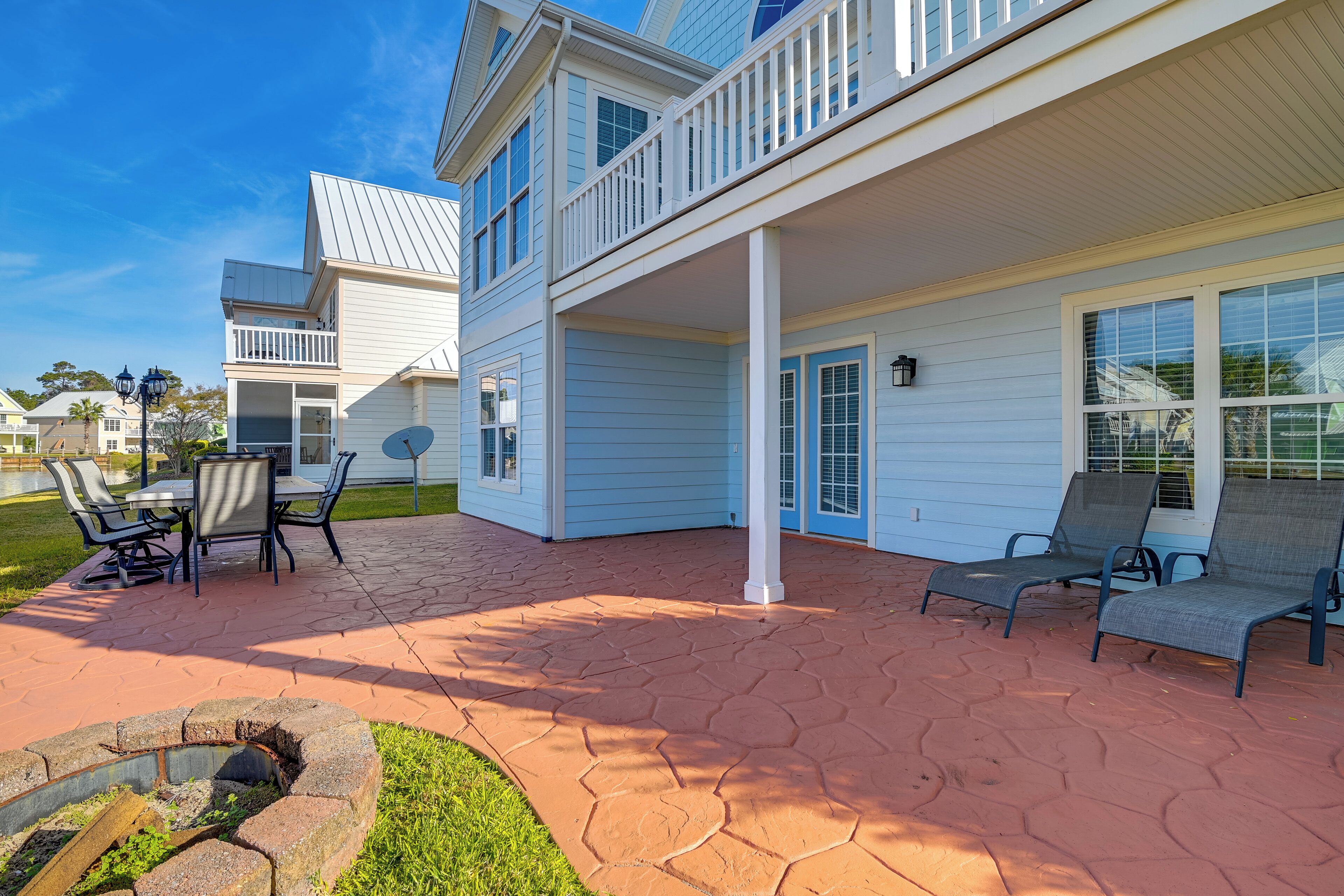 A two-story house with a covered patio, outdoor seating, and a fire pit.