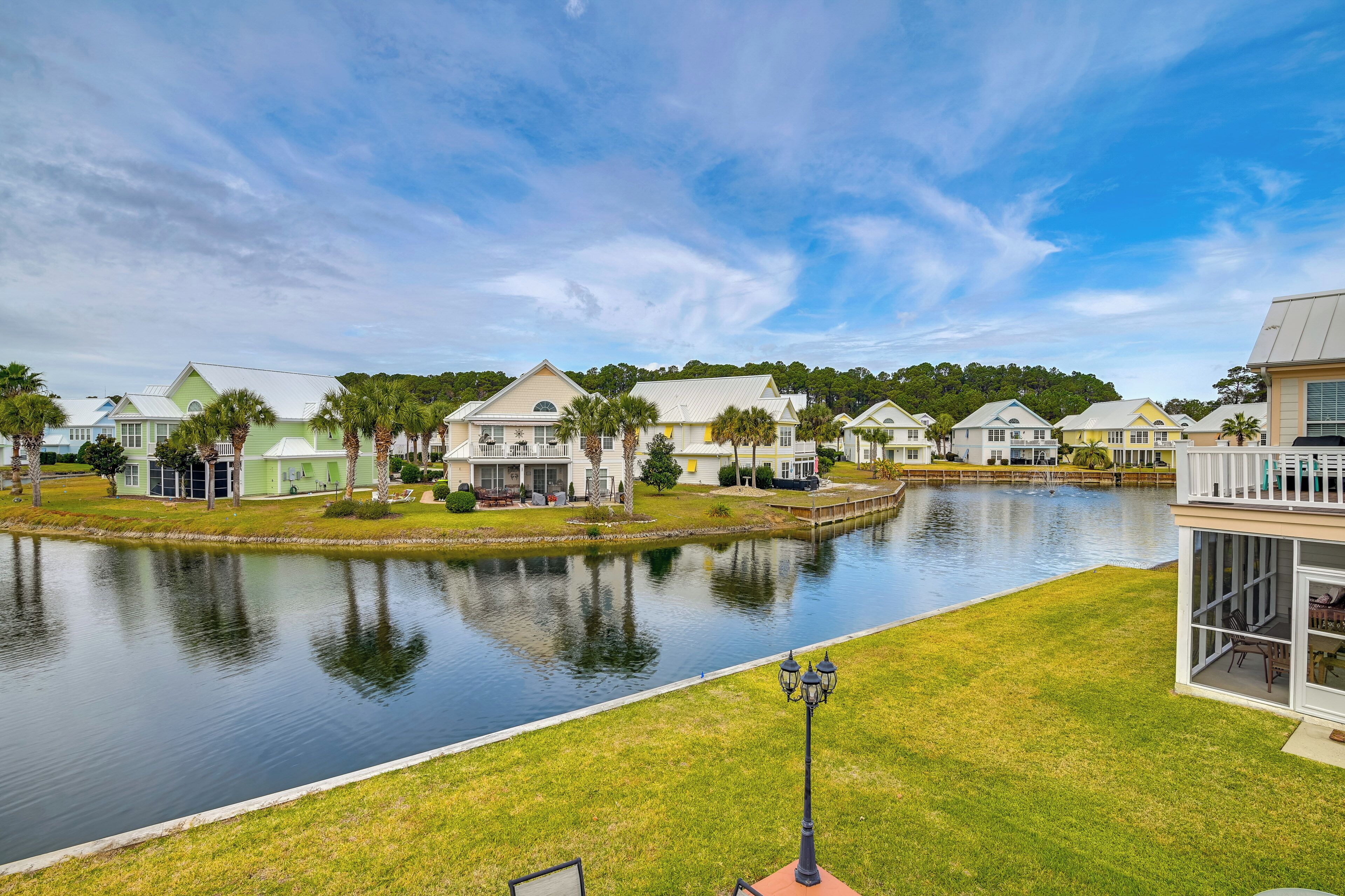 A waterfront residential area with houses, a calm lake, and a well-maintained lawn.