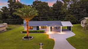 Una casa moderna con un césped cuidado, una construcción de un solo nivel y un porche cubierto.