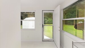 Una habitación con un amplio ventanal corredera que da a un espacio exterior con césped.