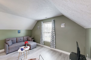 A cozy living room with a grey sofa, a small white table, and a TV.