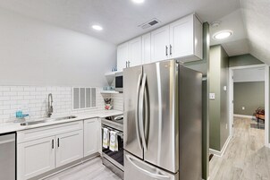 A modern kitchen with white cabinets, stainless steel appliances, and a tiled backsplash.