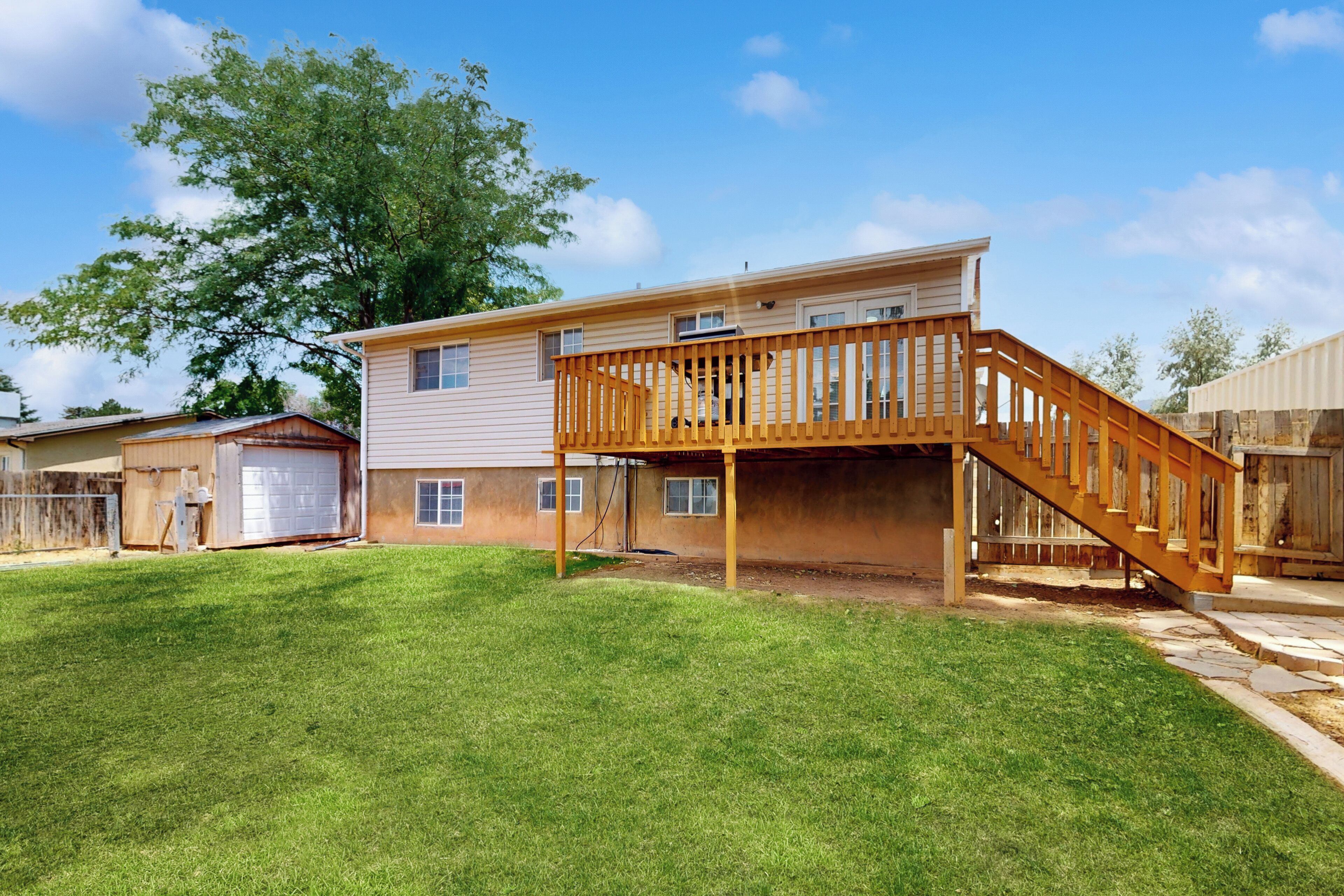 A two-story house with a wooden deck and a staircase.
