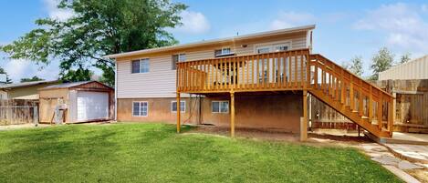 A two-story house with a wooden deck and a staircase.