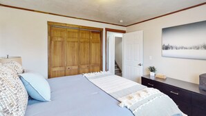 A bedroom with a bed, wooden wardrobe, a dresser, and a painting on the wall. - History, Hikes & Cozy Nights: Parowan Gem w/ Deck! (Parowan)