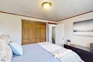 Un dormitorio con cama, armario de madera, cómoda y un cuadro en la pared.