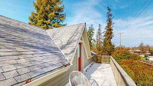 A covered outdoor area with a table and chairs, a sloped roof, and a view of trees and buildings in the background. - Forbestown Retreat: Easy Access to Clear Lake (Lakeport)
