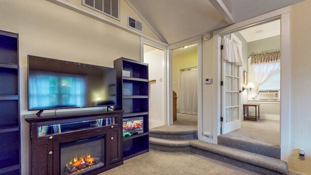 A living room with a fireplace, a television, and a staircase leading to another room. - Forbestown Retreat: Easy Access to Clear Lake (Lakeport)
