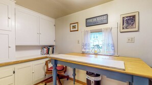A kitchen with white cabinets, a wooden countertop, a chair, and a window with curtains. - Forbestown Retreat: Easy Access to Clear Lake (Lakeport)