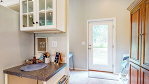 A kitchen with white cabinets, a granite countertop, and a door leading outside. - Homestead Cottage < 2 Mi to Salt Creek (Dallas)