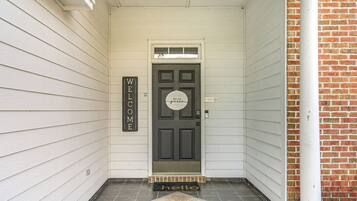 A front door with a 'WELCOME' sign, a 'hello' mat, and a 'Be our guest' sign.