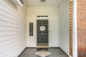 Una puerta principal con un cartel que dice 'WELCOME', un felpudo que dice 'hello' y un cartel que invita a 'Be our guest'.