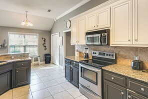 A kitchen with dark cabinets, a granite countertop, a stainless steel stove, and a microwave. - 3 BR Cozy Family Home w/ Playground (Valdosta)